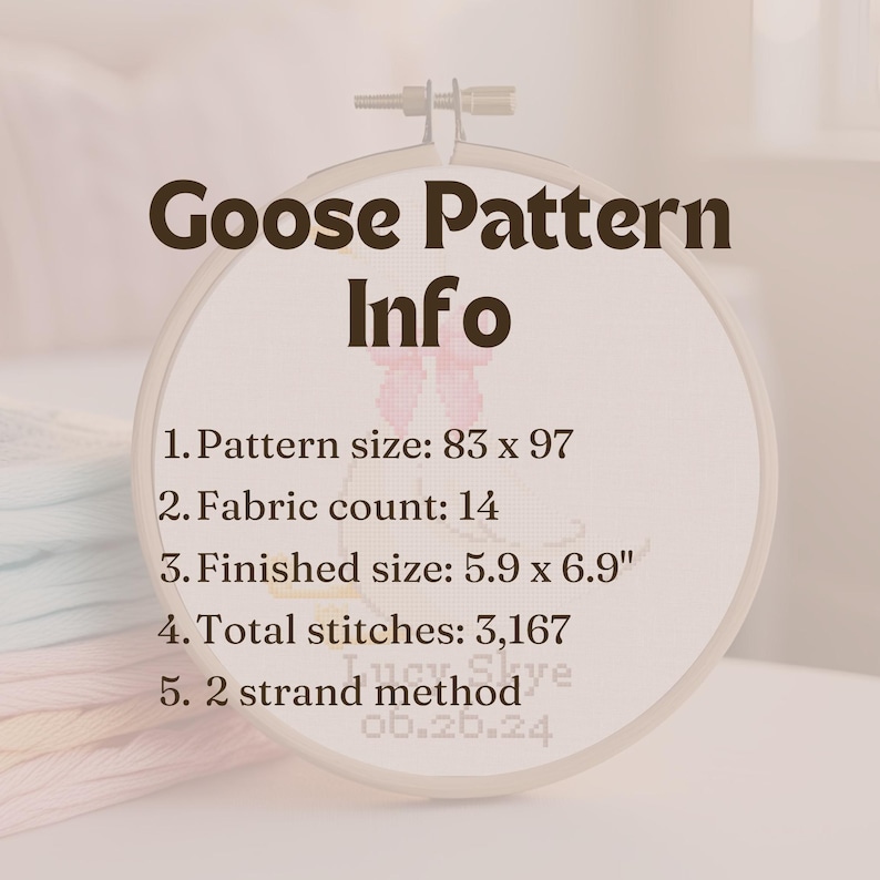 May include: A white embroidery hoop with the text "Goose Pattern Info" in brown text. The hoop contains information about the pattern size, fabric count, finished size, total stitches, and the method used for stitching. The text reads: "1. Pattern size: 83 x 97", "2. Fabric count: 14", "3. Finished size: 5.9 x 6.9"", "4. Total stitches: 3,167", "5. 2 strand method".