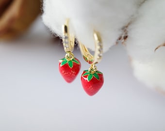 May include: A pair of gold hoop earrings with red and green enamel strawberry charms.