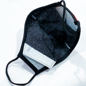 May include: Black face mask with a white PM2 filter insert. The mask has a black elastic strap and a black adjustable nose wire.