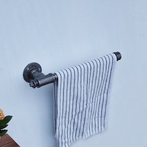 Può includere: Un portasciugamani in metallo nero con un asciugamano a righe bianche appeso.