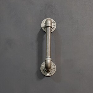 May include: A metal pipe handle with two round flanges. The flanges are marked with the numbers "1161" and "1161".