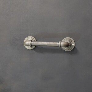 May include: A silver metal pipe with two round flanges. The flanges have the numbers "1914" and "081914" on them.