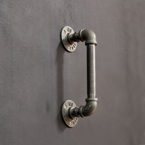 May include: A black metal industrial style door handle with a pipe design. The handle has two round flanges with the text "08" and "01" on them.