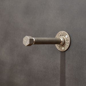 Peut inclure: Un support d'étagère en métal argenté avec un embout hexagonal et une bride ronde. La bride porte l'inscription "US" et "1/2".