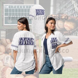 May include: White baseball jersey with vertical pinstripes and the text "FANTASY READER" in navy blue. The jersey has navy blue stitching details and is worn open over a navy blue top and blue jeans. The jersey is displayed on a person.