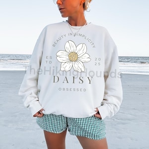 Puede incluir: Sudadera blanca con un gráfico de margarita y el texto "Beauty in Simplicity Est. 2025 Daisy Obsessed".