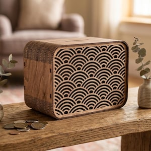 May include: A rectangular wooden money box featuring a laser-cut front panel with a repeating black and brown arched wave pattern. The box has rounded corners, a coin slot on the top surface, and visible wood grain texture on the side panels.