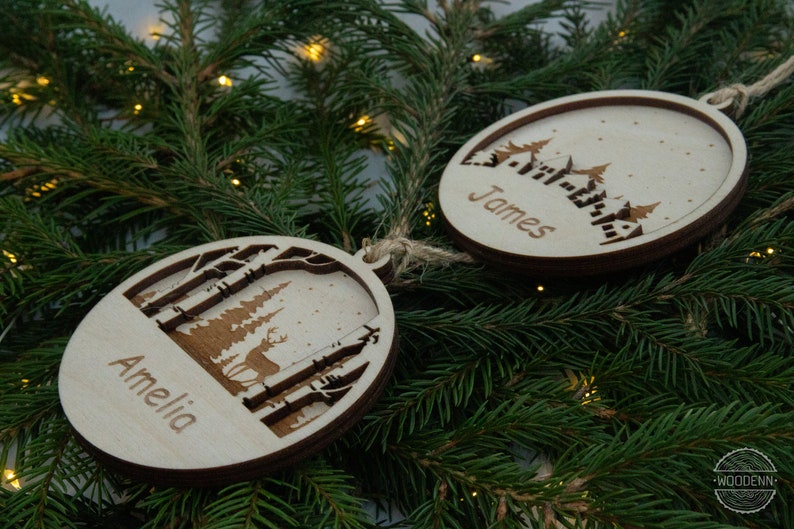 Pu&ograve; includere: Due decorazioni natalizie in legno con un design a tema invernale. Un ornamento ha il nome "Amelia" e l'altro il nome "James".