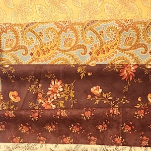 May include: A collection of fabric strips with various floral patterns in shades of brown, yellow, and green. The fabrics feature designs of leaves, berries, paisley, and birds.