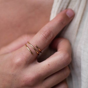 May include: A close-up of a person's hand wearing a gold, triple-band ring.