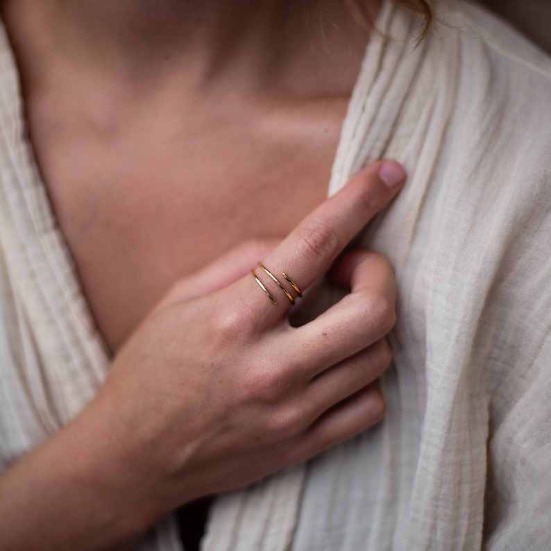 May include: A close-up of a person's hand wearing a gold, triple-band ring.
