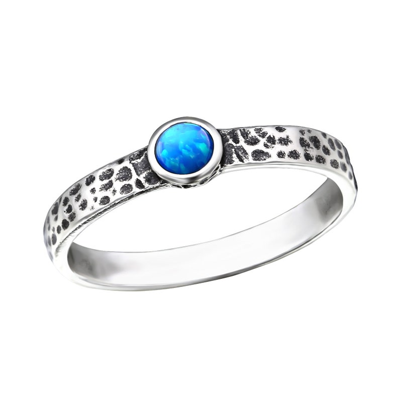 May include: A silver ring with a textured band and a blue opal gemstone.