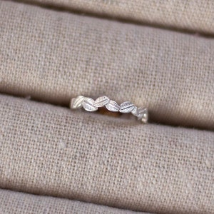 May include: A silver ring with a delicate leaf design. The ring is simple and elegant, perfect for everyday wear.