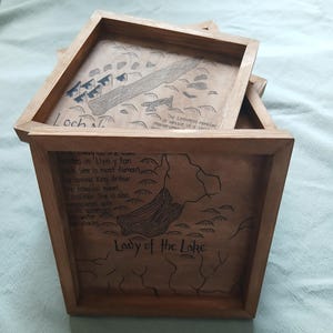 May include: Wooden framed trays with hand-drawn maps and text. One tray features a map labeled "Loch Ness" with the text "The Lochness monster or Nessie is a large marine creature." Another tray says "Lady of the Lake."