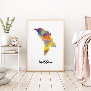 May include: A watercolour print of the country of Moldova in a gold frame. The map is painted in shades of blue, yellow, orange, and red. The word "Moldova" is written in black script below the map.