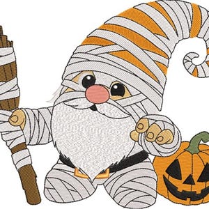 Könnte beinhalten: Ein gestickter Halloween-Zwerg, der als Mumie verkleidet ist, einen Besen hält und neben einem geschnitzten Kürbis steht. Der Zwerg hat einen weißen Bart, eine rosa Nase und einen gewickelten Hut mit orangefarbenen Streifen.
