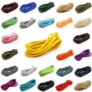 Könnte beinhalten: Eine Sammlung von fünfundzwanzig einzelnen Rollen aus rundem Kordelmaterial in verschiedenen Unifarben wie Gelb, Rot, Blau, Grün, Schwarz, Weiß, Braun, Rosa, Orange und Violett, die in einem Raster auf weißem Hintergrund angeordnet sind.