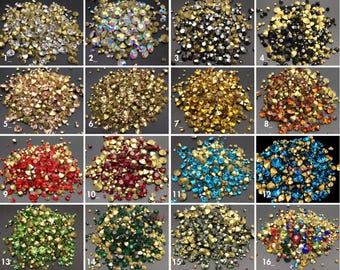 May include: Assortment of 16 different colors of rhinestones, each color is displayed in a separate pile. The rhinestones are small and have a variety of shapes and sizes.