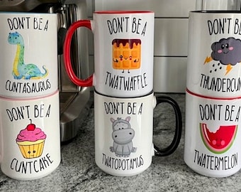 Könnte beinhalten: Sechs weiße Keramikbecher mit schwarzen Griffen und bunten Akzenten. Jeder Becher hat eine andere humorvolle Grafik und einen anderen Text. Der Text auf den Bechern lautet "Sei kein" gefolgt von einem humorvollen Wort. Die Becher sind in zwei Reihen zu je drei angeordnet.