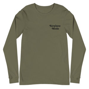 以下が含まれることがあります： 前面に黒で「Airplane Mode」とプリントされた、長袖のアーミーグリーンのTシャツです。