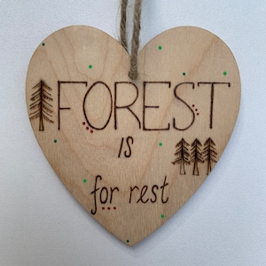 May include: A wooden heart-shaped ornament with the text "FOREST is for rest" burned into the surface. The ornament is decorated with green and red dots and features a small tree design.