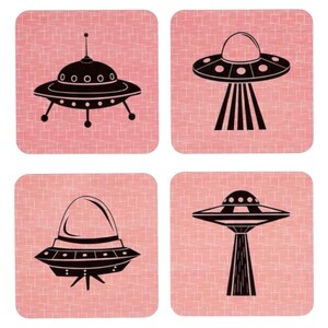 Four square coasters with rounded corners, each featuring a different black UFO illustration on a pink background with a subtle grid pattern.