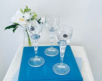 May include: Three clear glass stemmed drinking glasses with a twisted stem design. The glasses are sitting on a blue book with the text "The World's Whales" and "Gardening" visible.