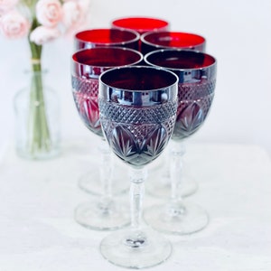 Pode incluir: Conjunto de seis copos de vinho tinto escuro com design de vidro cortado. Os copos têm uma haste e uma base transparentes.