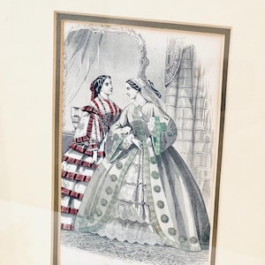 K&ouml;nnte beinhalten: Ein Vintage-Schwarzwei&szlig;druck von zwei Frauen in aufwendigen Kleidern. Die Frau links tr&auml;gt ein rot-wei&szlig; kariertes Kleid mit einer schwarzen Sch&auml;rpe. Die Frau rechts tr&auml;gt ein graues Kleid mit gr&uuml;n-schwarzen Karomustern. Beide Frauen stehen in einem Raum mit einem Spiegel und einem Fenster.