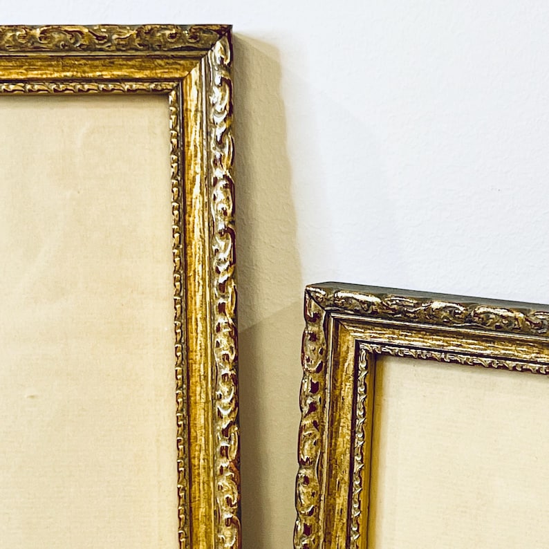 K&ouml;nnte beinhalten: Zwei verzierte goldene Bilderrahmen mit einem dekorativen, erhabenen, gemusterten Rand. Die Rahmen sind leer und bereit, Kunstwerke oder Fotos zu pr&auml;sentieren.