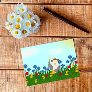 Puede incluir: Una ilustración caprichosa de un pájaro con un sombrero y sosteniendo un diente de león, rodeado de flores azules y amarillas en un campo.