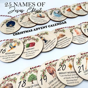 May include: A set of 25 circular wooden ornaments for a Christmas advent calendar, each featuring a unique illustration, a number from 1 to 25, and the text 25 Names of Jesus Christ. The ornaments are strung together with red and white twine.