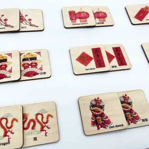 May include: A set of square wooden tiles featuring illustrations related to Chinese New Year, including peach blossoms, lanterns, red pockets, firecrackers, dragons, lion dances, and figures with text labels in English and Chinese characters.