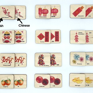 May include: A set of rectangular wooden tiles featuring illustrations of Lunar New Year symbols including peach blossoms, lanterns, red pockets, firecrackers, dragons, lion dancers, fireworks, tangerines, candy boxes, and gold ingots with English and Chinese text.