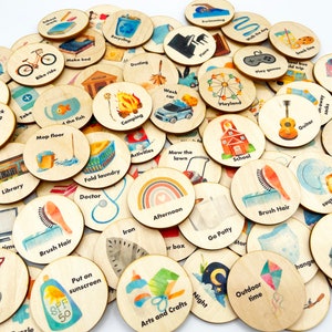 May include: A collection of 36 round wooden tokens with various images and text. The tokens are painted with watercolor illustrations of activities, chores, and routines. Some of the text on the tokens includes 'Brush Hair', 'Mow the Lawn', 'Camping', 'School', 'Guitar', 'Playland', 'Take a Bath', 'Put on Sunscreen', 'Arts and Crafts', 'Night', 'Outdoor Time', 'Trim Nails', 'Music', 'Laundry', 'Go Potty', 'Iron', 'Afternoon', 'Fold Laundry', 'Doctor', 'Library', 'Shovel Snow', 'Pack Bag', 'Make Bed', 'Bike Ride', 'Dusting', 'Swimming', 'Walk the Dog', 'Snack Time', 'School Trip', 'Play Games', 'Pajamas', 'Wash Car', 'Activities', 'Map Floor', '4 the Fish', 'Brush Teeth', 'Pack Bag', 'Take a Bath'.