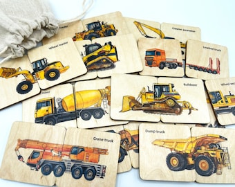 May include: A collection of square wooden tiles featuring colorful illustrations of construction vehicles including a wheel loader, crawler excavator, lowbed truck, mixer, bulldozer, and crane truck, each labeled with its corresponding name in black text.