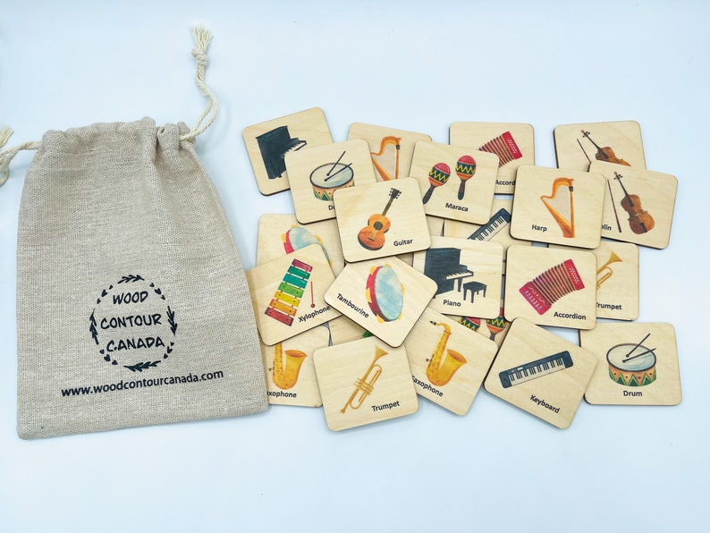 May include: A beige drawstring linen bag with the text WOOD CONTOUR CANADA and a website URL, accompanied by a collection of square wooden tiles featuring colorful illustrations of various musical instruments like guitars, drums, and pianos.