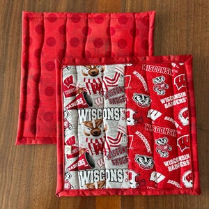 May include: Two red and white fabric pot holders. One is red with white polka dots. The other is white with red and gray Wisconsin Badgers logos and the words "Wisconsin Badgers".