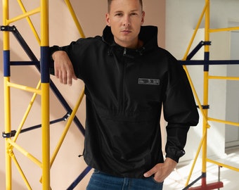 May include: Black hooded jacket with a front pocket and a small rectangular logo. The jacket has a zipper closure and long sleeves. The person in the image is wearing blue jeans. The background includes yellow and blue scaffolding.
