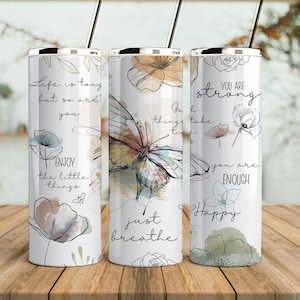 May include: Three stainless steel tumblers with inspirational quotes and floral designs. The tumblers feature quotes like "Life is tough but so are you", "Go with the flow, things take time", and "You are strong, you are enough, Happy".