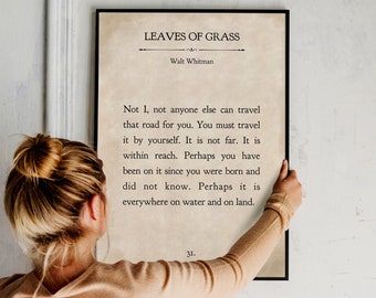 Op de afbeelding: Een ingelijste print van een gedicht van Walt Whitman, "Leaves of Grass", met de tekst "Not I, not anyone else can travel that road for you. You must travel it by yourself. It is not far. It is within reach. Perhaps you have been on it since you were born and did not know. Perhaps it is everywhere on water and on land." De print is op een beige achtergrond met zwarte tekst.