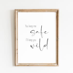 May include: A framed print with the text "You keep me safe, I'll keep you wild" in black cursive font on a white background.