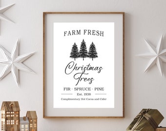 May include: A framed print with the text "FARM FRESH Christmas Trees" and three evergreen trees. The print is displayed on a wooden mantel with decorative stars and miniature houses. A wrapped gift box sits on the mantel.