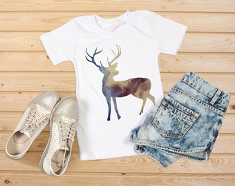 May include: A white t-shirt with a watercolor deer silhouette design. The shirt is paired with light blue denim shorts and white sneakers.
