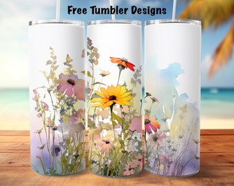 May include: Three stainless steel tumblers with a watercolor design of wildflowers in shades of yellow, pink, and orange. The tumblers are on a wooden surface with a beach scene in the background.