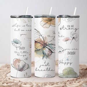 May include: Three stainless steel tumblers with motivational quotes and floral designs. The tumblers feature quotes like "Life is tough, but so are you", "Good things take time", and "You are strong, you are enough".