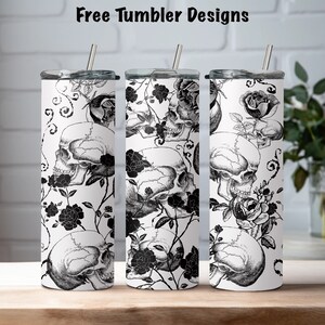 May include: Three stainless steel tumblers with black and white designs featuring skulls and roses. The tumblers are on a wooden surface.