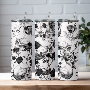 May include: Three stainless steel tumblers with black and white floral and skull designs. The tumblers have lids and straws.