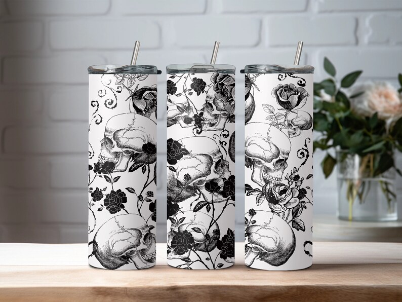 May include: Three stainless steel tumblers with black and white floral and skull designs. The tumblers have lids and straws.