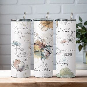 May include: Three stainless steel tumblers with motivational quotes and floral designs. The tumblers feature quotes like "Life is tough, but so are you", "Go, thing, take time to breathe", and "You are strong, you are enough, Happy".
